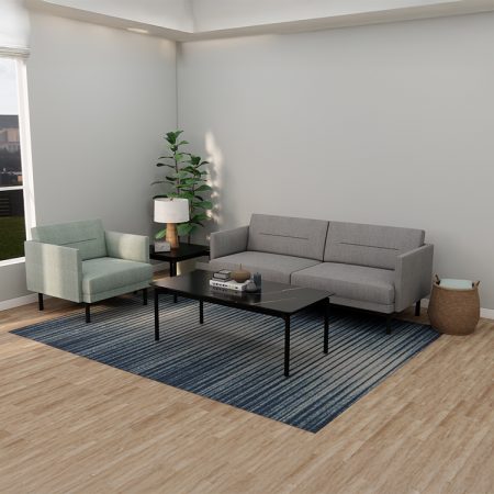 A modern living room features a gray sofa, a light green armchair, and a black coffee table on a blue gradient rug. A floor lamp and a tall plant are in the corner, with a basket nearby. Sunlight streams through a window, illuminating the space.