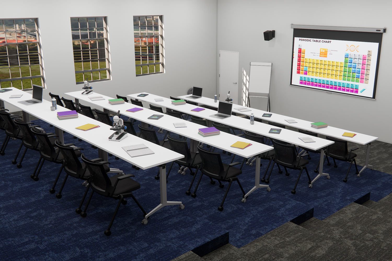 A modern classroom with long white desks arranged in rows, each with black chairs, books, and microscopes. A large screen at the front displays the periodic table. Sunlight filters through the windows onto blue carpet flooring.